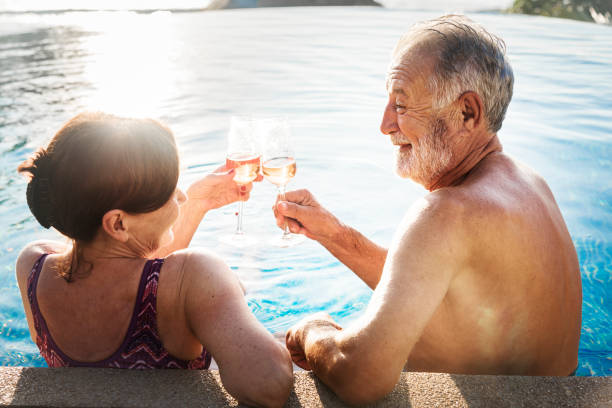 ein flitterwochenpaar, das den sommer genießt - active seniors retirement enjoyment swimming pool stock-fotos und bilder