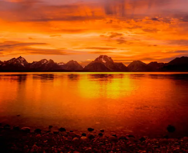 Photo of Grand Tetons Range  and orange sunset at Jackson Lake, WY