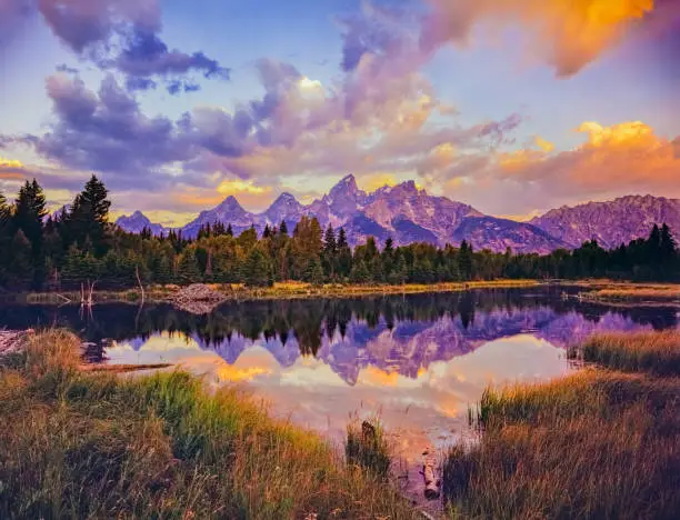 Photo of Beaver pond glows in orange sunset at Grand Teton National Park