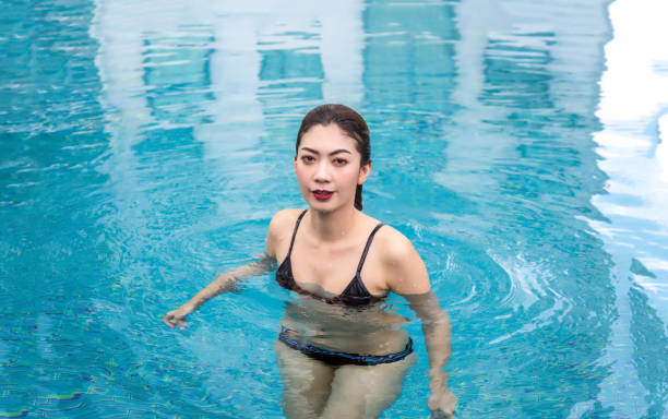 istock asian lady in swimming suite posting water pool. 976460248