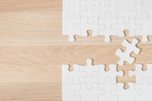 istock Jigsaw puzzle game piece on light cream brown wood texture background 976477274