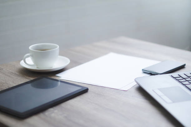 istock Blank office desk with coffee cup tablet smartphone laptop computer in working space 976495172