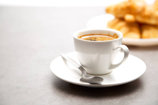Cup of fresh hot coffee with croissants on dark wood background
