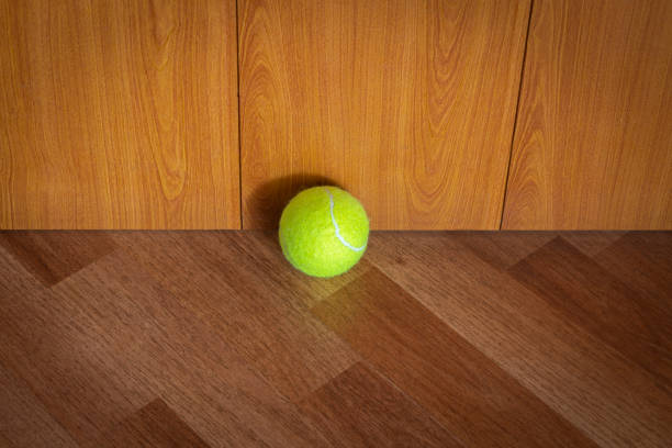 A tennis ball lies in the corner of the room.