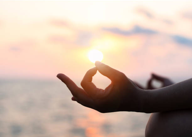 mantra yoga méditation pratique avec la silhouette de femme en lotus posent avoir détente esprit paisible sur la formation en plein air de plage avec ciel céleste de l’heure du coucher du soleil d’or - nirvana photos et images de collection