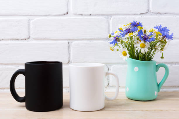 istock White and black mug mockup with cornflower and daisy 976544344
