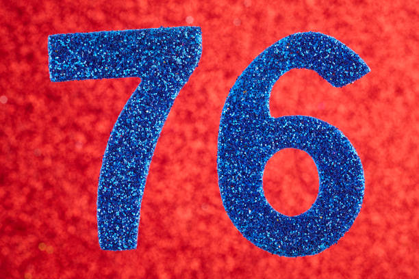 istock Number seventy-six blue color over a red background. Anniversary 976557472