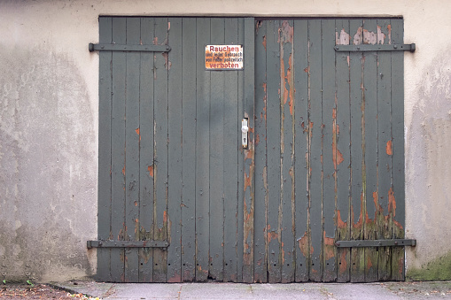 Old gray wooden garage door with sign forbidden by smoking