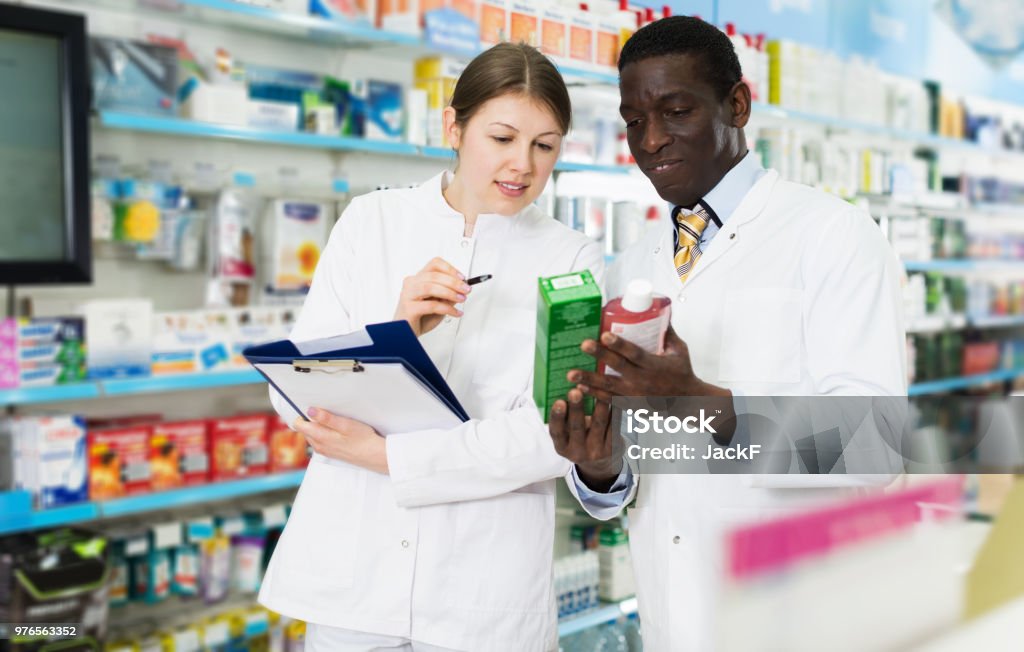 farmacisti che prendono l'inventario dei medicinali in farmacia - Foto stock royalty-free di Farmacia