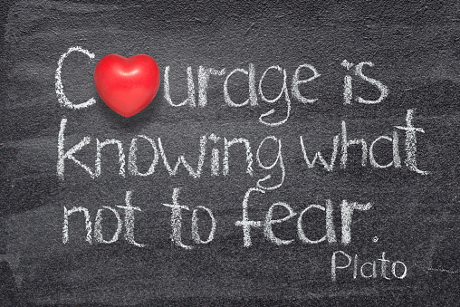 Courage is knowing what not to fear quote of ancient Greek philosopher Plato written on chalkboard with red heart symbol instead of O