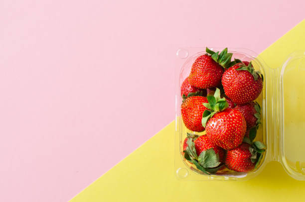 istock Fresh ripe strawberries in plastic container on duotone background. Top view and copy space. Organic food concept. 976576294