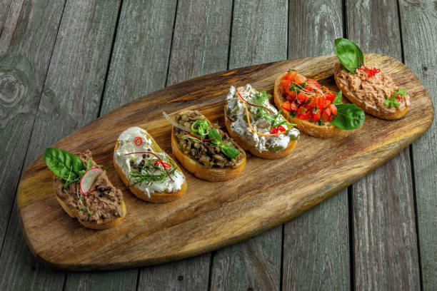 Antipasti bruschetta set Bruschetta set made of tomato, meat pate, olives, cream cheese and tuna salad on a rustic wooden board. Delicious Italian antipasti. Top view. tuna pate stock pictures, royalty-free photos & images