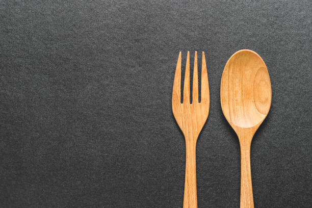istock wooden  fork and spoon on black table, top view. 976585714