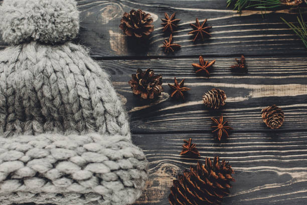 istock warm cozy woolen hat with anise and pine cones on rustic background top view, space for text. hipster stylish simple cloth flat lay. seasonal greetings. holiday mood 976585924