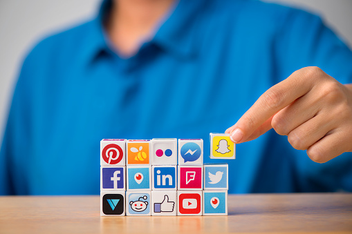 Antalya, Turkey - June 14, 2018: A hand touching plastic cubes with popular social media services icons, including Facebook, Instagram, Youtube, Twitter on a white background.
