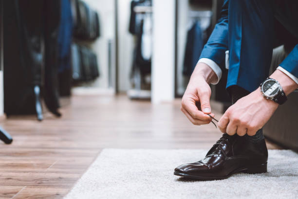 Luxury retail store Man dressed in an elegant business suit is trying on shoes to go with the suit. They must be comfortable and elegant looking at the same time. mens fashion stock pictures, royalty-free photos & images