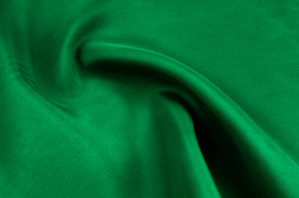 istock Background texture, pattern. Thick thick silk fabric is green. This satin fabric is ideal for creating a smooth flow in design, it has a liquid drape and exquisite shine. 976611636