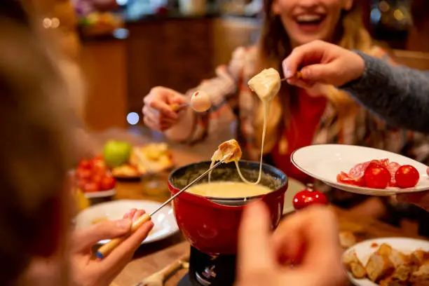 A group of work colleagues eat fondue together on a team bonding trip.