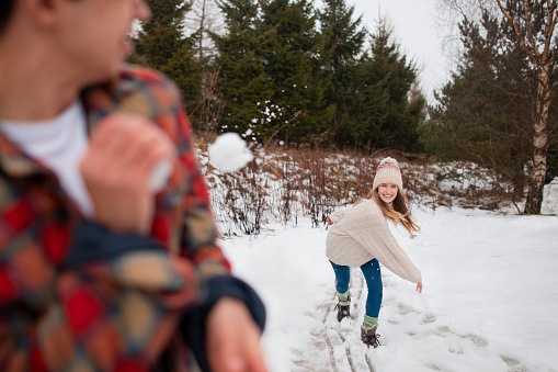 A young woman throws a snowball at her work colleague whilst on a team bonding trip.