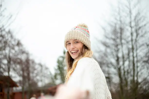 A young woman smiles at the camera whilst walking through the snow on a ski holiday.