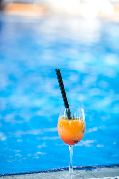istock orange cocktail on swimming pool background.Summer vacation concept. Refreshing beverage.vertical shot. copy space 976653214