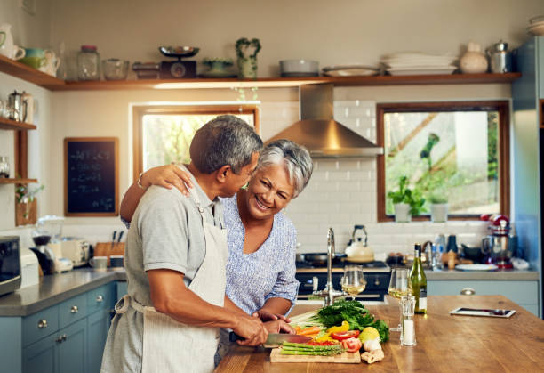 Home cooked happiness Shot of a happy mature couple cooking a meal together at home chopping food photos stock pictures, royalty-free photos & images
