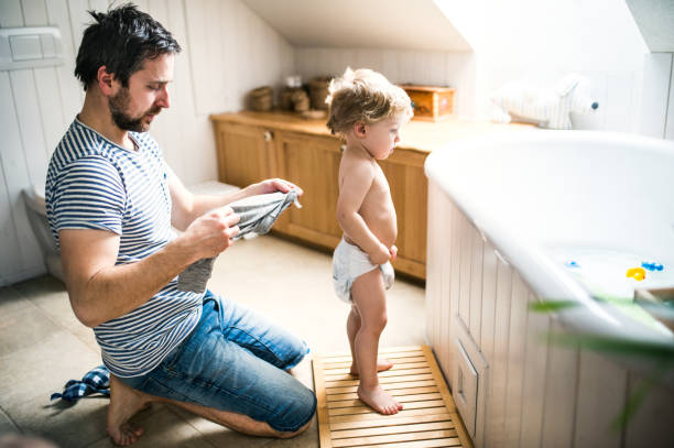 padre con un bambino bambino a casa, che si prepara per un bagno. - bathtub child bathroom baby foto e immagini stock