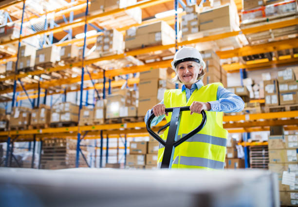 istock A senior woman warehouse worker pulling a pallet truck with boxes. 976670098