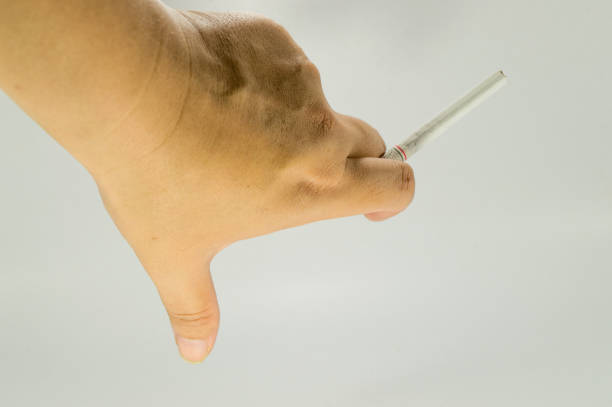 istock Hand holding a cigarette. Unlighted cigarette holden between two fingers. 976670634