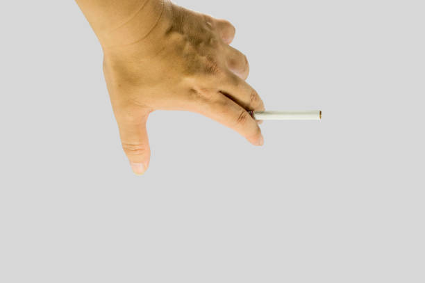 istock Hand holding a cigarette. Unlighted cigarette holden between two fingers. 976670704