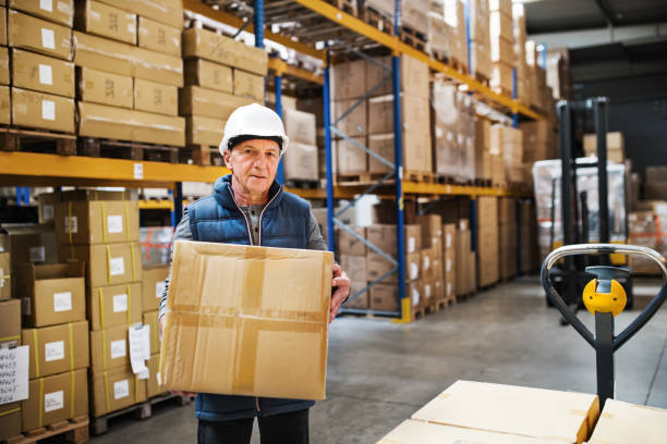 istock Senior male warehouse worker unloading boxes from a pallet truck. 976671454