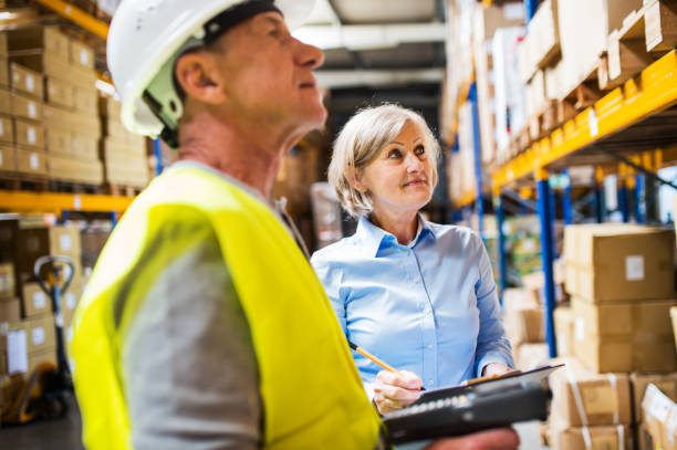 istock Senior woman manager and man worker working in a warehouse. 976679100