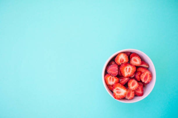 istock Strawberry in a bowl on blue background. 976679660