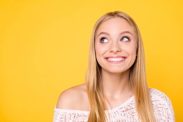 retrato de menina sorridente alegre com ombro nu, olhando com olhos no lugar vazio copyspace, tendo dentes brancos direto saudáveis, isolados em fundo amarelo - teenager teenage girls women dentist - fotografias e filmes do acervo