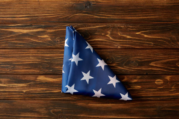 повышенный вид сложенного флага соединенных штатов на деревянной поверхности - american flag folded usa flag стоковые фото и изображения