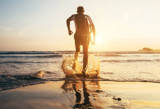 istock Surfer with surfboard runs in to the ocean waves 976715278