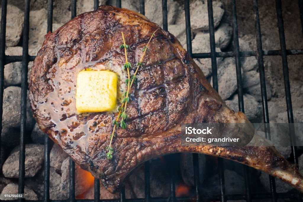 Rib Eye Beef Steak with Melted Butter on a Grill Delicious grass fed rib eye steak on a grill ready to be eaten.  Beef is a great ingredient to a ketogenic diet Rib Eye Steak Stock Photo