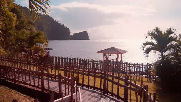 Photo of Zig zagging walkway leading down to a tropical beach with the ocean in the background. Concept of summer fun