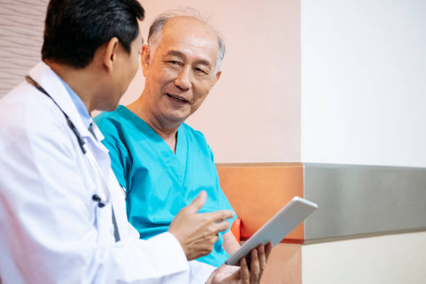 Senior man listening to doctor with tablet Medical consultant talking to cheerful man with relieved expression kuala lumpur photos stock pictures, royalty-free photos & images