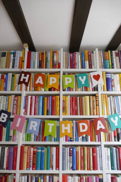 lettere di buon compleanno appese alla libreria in biblioteca - book book spine in a row library foto e immagini stock