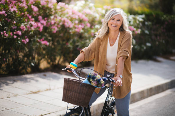 smiling senior woman having fun riding vintage bike in spring - beautiful one person caucasian beauty imagens e fotografias de stock
