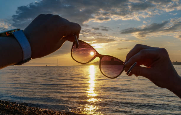 istock Sunset through the sun glasses in hands, sea background 976792494