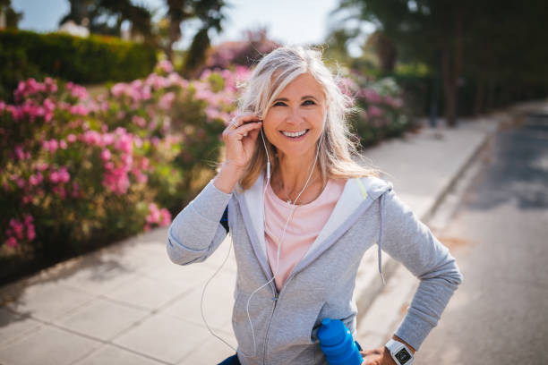 portrait de femme mature active, écouter de la musique avant de faire du jogging - headphones relaxation outdoors caucasian photos et images de collection