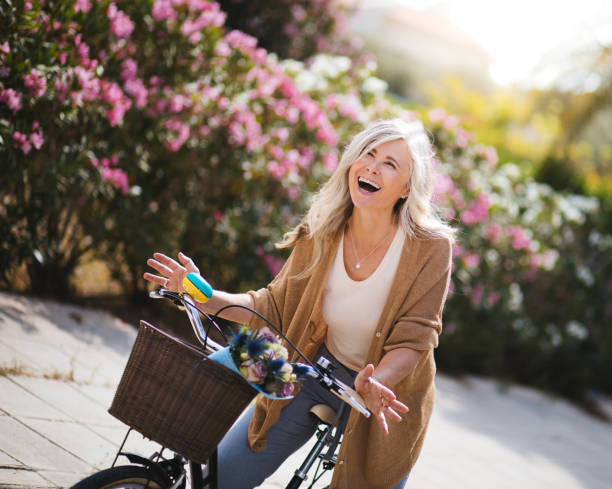 donna felice matura che si gode il giro in bicicletta con la bicicletta d'epoca - bicycle ride foto e immagini stock