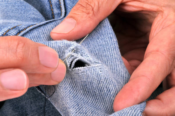 Sew jeans close-up of someone sewing up jeans hole in pants stock pictures, royalty-free photos & images