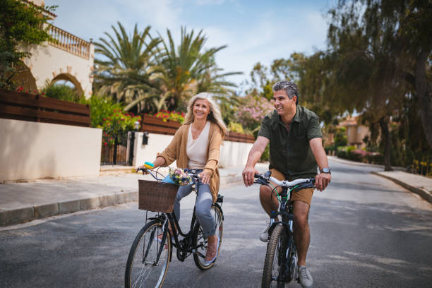 activo pareja senior, montar en bici en la calle suburbana en primavera - men gray hair vitality healthy lifestyle fotografías e imágenes de stock