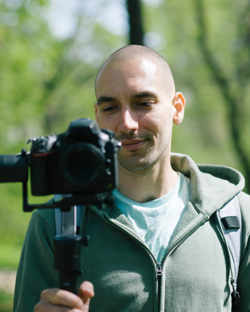 istock Young man holding camera and taking photo outdoors 976805846