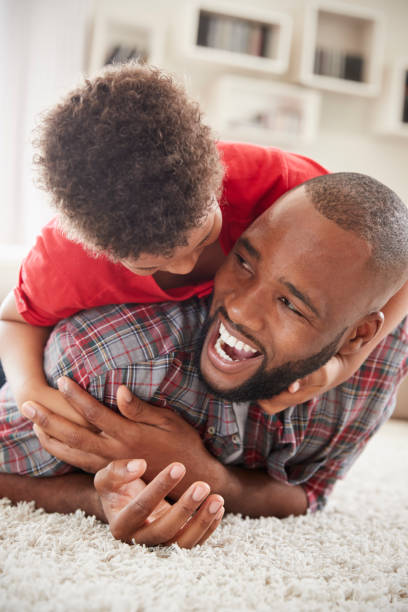 istock Son Climbs On Fathers Back As They Play Game In Lounge Together 976807638