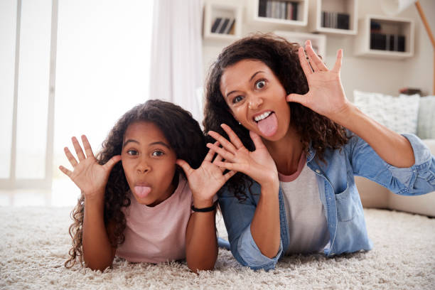 istock Mother And Daughter Lying On Rug And Pulling Faces At Home 976807864