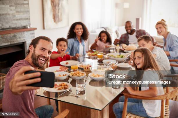 Due Famiglie Che Si Fanno Selfie Mentre Si Godono Il Pasto A Casa Insieme - Fotografie stock e altre immagini di Famiglia